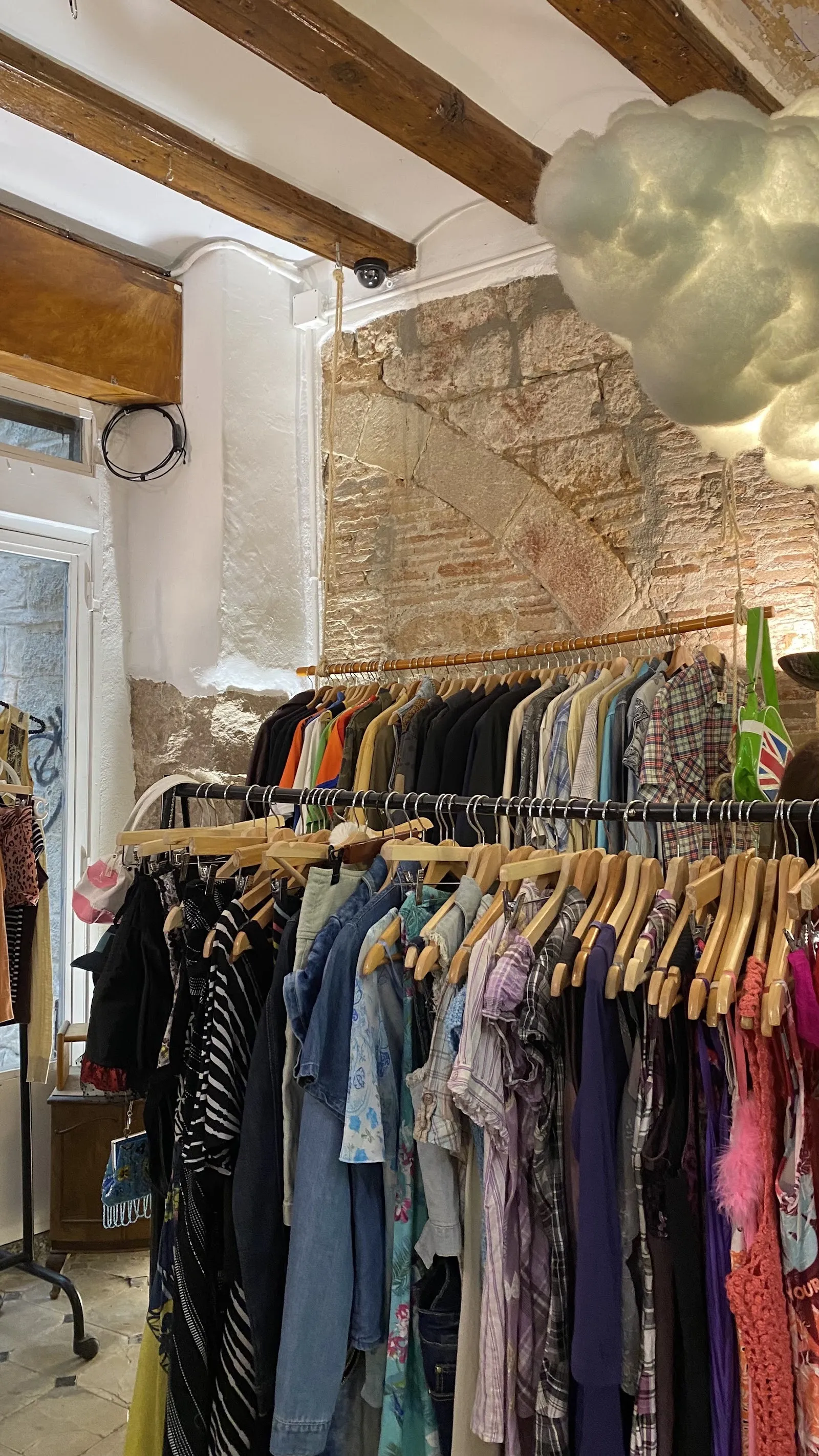 A long rail of tops and dresses under the stone arch of the Born shop