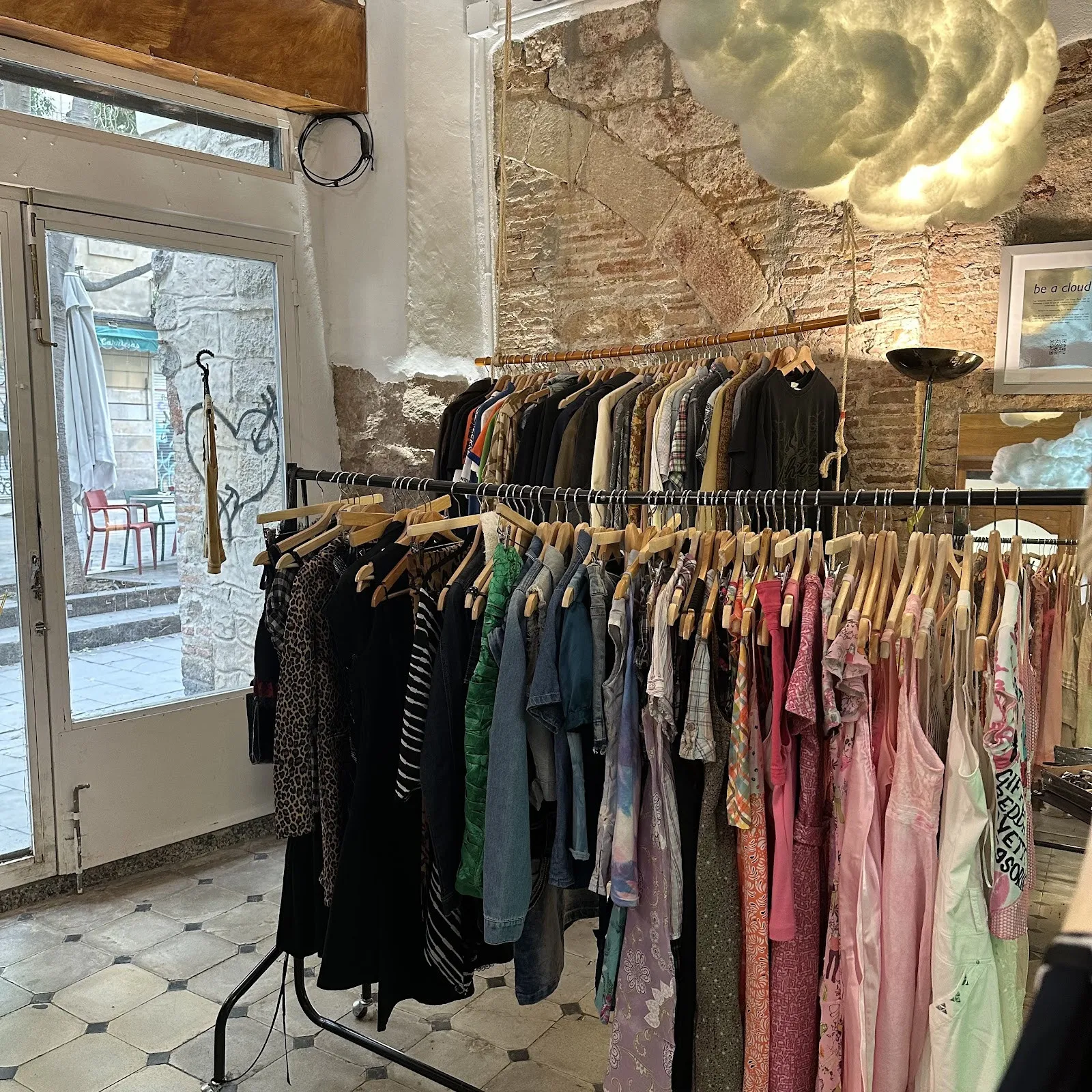 Rails of colourful clothes by the glass doors of the Born shop, a cloud lamp above