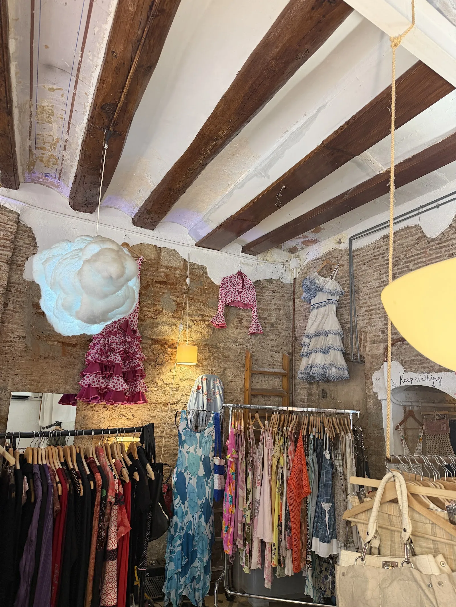 Inside Zoetrope Vintage in the Born: wooden ceiling beams, a white cloud hanging over rails of dresses